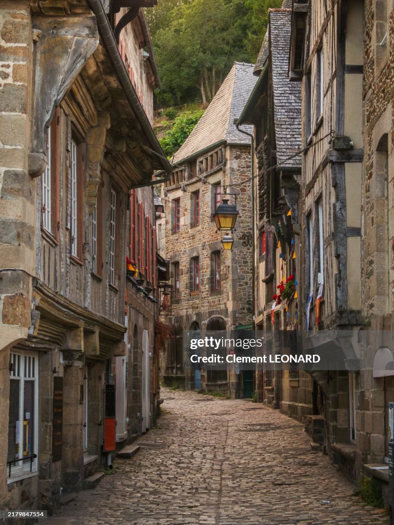 View of an empty uphill cobblestone street in the medieval old town of Dinan at sunset, lined with traditional Breton stone and half-timbered houses, Cotes-d'Armor - Bretagne (Brittany) - Western France.