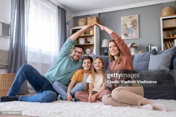 a young family forming a house shape with hands - home insurance stock pictures, royalty-free photos & images