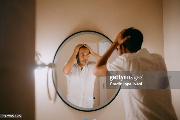 man worrying about his hair - parcialmente calvo fotografías e imágenes de stock