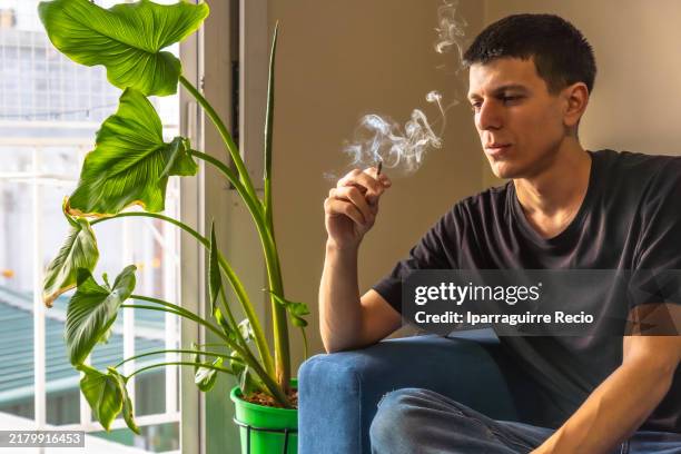 young student man smoking a joint of marijuana - spinello foto e immagini stock