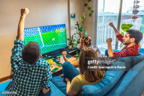 friends celebrating victory watching sports on television - difusão de televisão imagens e fotografias de stock