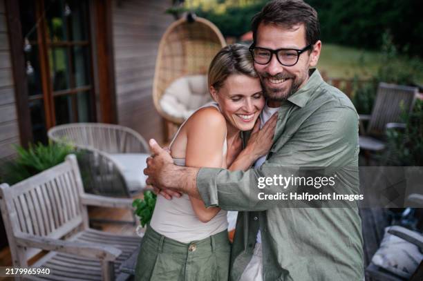husband and wife hugging tightly. hygge moment for couple in love, standing outdoor on patio and having romantic moment. - mid adult couple stock pictures, royalty-free photos & images