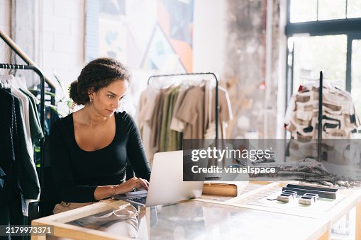 Female clothing shop owner managing her online store on a laptop Female clothing shop owner managing her online store on a laptop