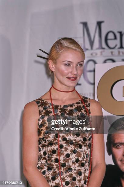 American actress Cameron Diaz, wearing a sleeveless dress with a brown, black and cream pattern, a long red necklace, and a pale blue shawl, attends...