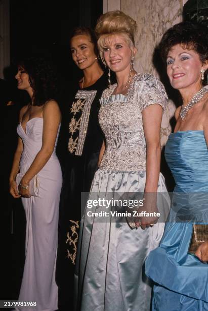 American actress Jaclyn Smith, wearing a white evening gown, American actress and model Margaux Hemingway, who wears a black outfit with silver and...
