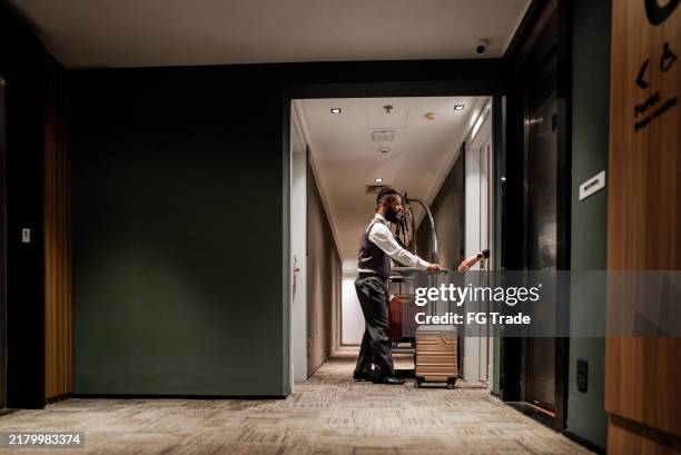 bellhop delivering suitcase to customer at a hotel - bellhop stock pictures, royalty-free photos & images