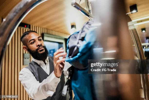 bellhop organizing luggage cart at a hotel - bellhop stock pictures, royalty-free photos & images