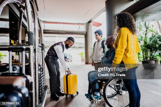 hotelpage, der kunden in der eingangshalle eines hotels bedient - hotel page stock-fotos und bilder