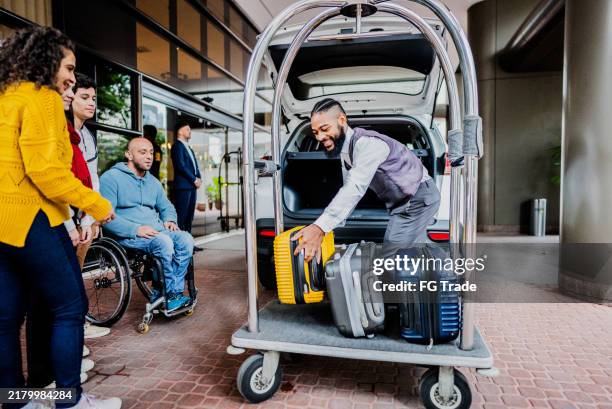 botones descargando maletas de clientes en el hall de entrada de un hotel - carrito-para-equipaje fotografías e imágenes de stock