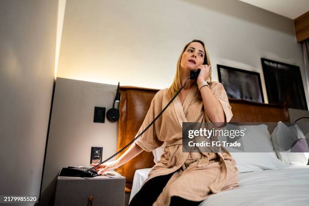 reife frau, die in einem hotel telefoniert - hotelzimmer stock-fotos und bilder