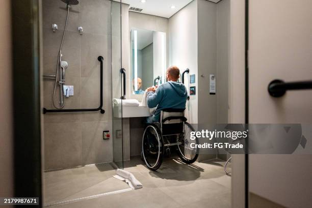 mature man drying his hands in the bathroom - tillgänglighet för personer med funktionsnedsättning bildbanksfoton och bilder