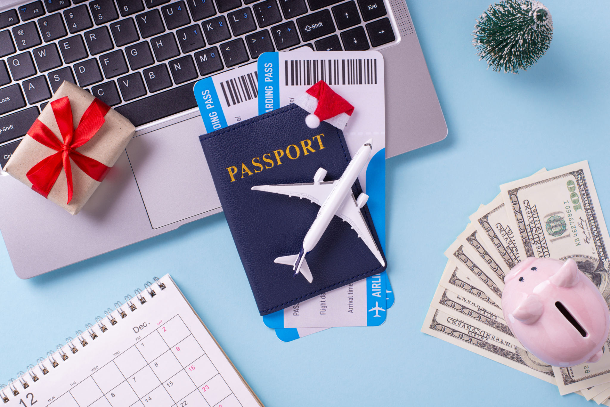 An overhead view of travel essentials including a passport, boarding passes, small airplane model, gift, and money, ideal for holiday travel planning An overhead view of travel essentials including a passport, boarding passes, small airplane model, gift, and money, ideal for holiday travel planning