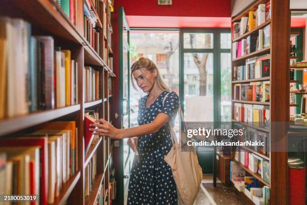 a woman looking for the right tittle in a local bookstore - book shop stock pictures, royalty-free photos & images