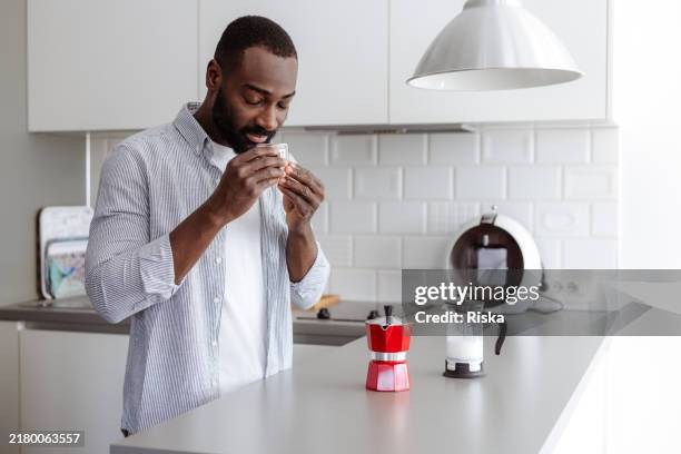 man savoring coffee aroma in modern kitchen setting - french press stock pictures, royalty-free photos & images