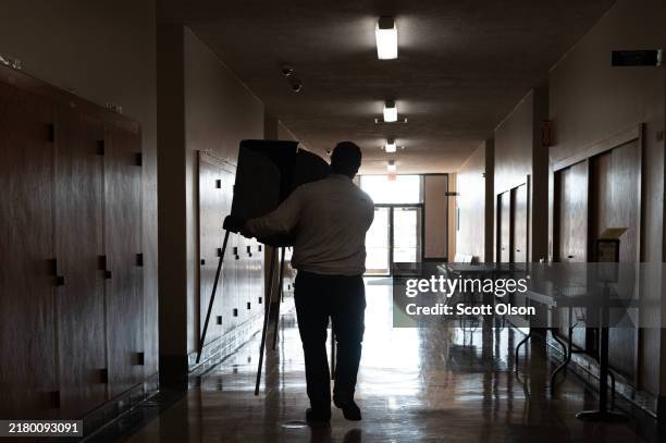 Aiden Stahl, an intern with the election division of the Kenosha County clerk's office, sets up voting booths in a hallway of the Kenosha Municipal...
