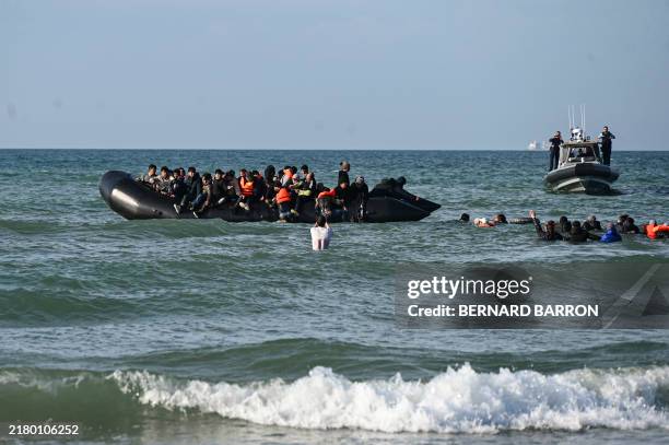Migrants swim to board a smugglers' boat in order to attempt crossing the English channel off the beach of Audresselles, northern France on October...