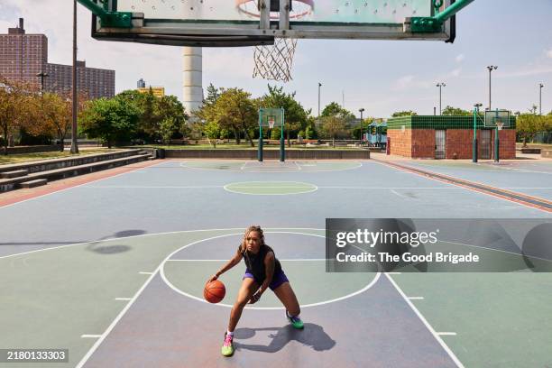 young woman playing basketball at park in city - basquetebol feminino imagens e fotografias de stock