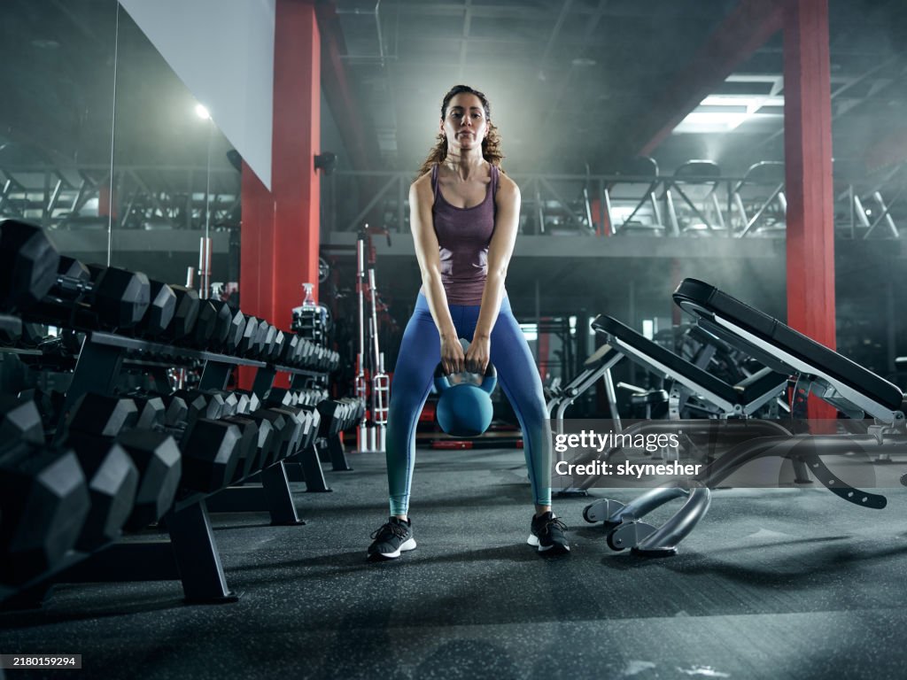 Athletic woman having strength training with kettle bell in a health club.