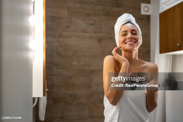 la donna contenta nutre il viso nel caldo bagliore dello specchio - real woman foto e immagini stock