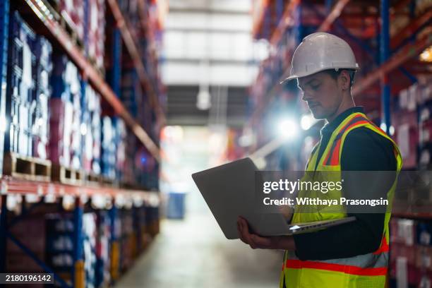 warehouse worker using laptop for inventory management - industrie-lourde photos et images de collection