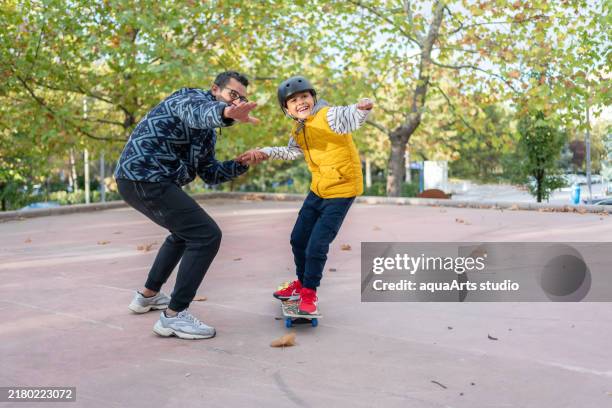 father and son enjoying skateboarding together at a skate park - skateboard stock pictures, royalty-free photos & images