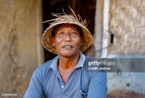 portrait of a balinese man wearing a hat while sitting outside his house - indonesian culture stock pictures, royalty-free photos & images