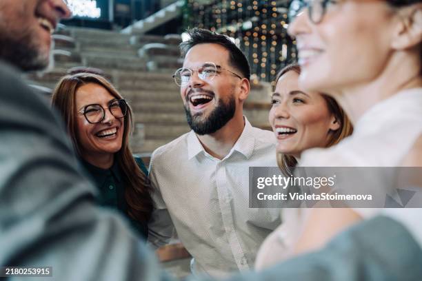 aufgeregte kollegen, die sich während einer feier im büro umarmen. - feiern stock-fotos und bilder