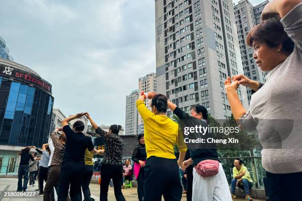 Group of women participate in a public dance session in a square surrounded by high-rise buildings on October 22, 2024 in Chongqing, China. Public...