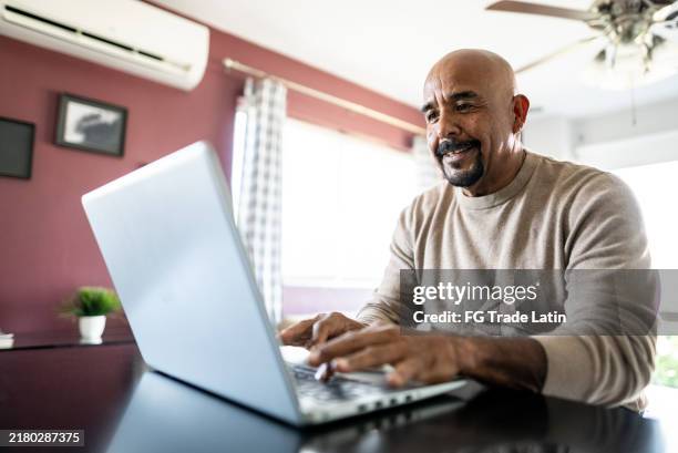 senior man using laptop at home - mexican people laptop stock pictures, royalty-free photos & images
