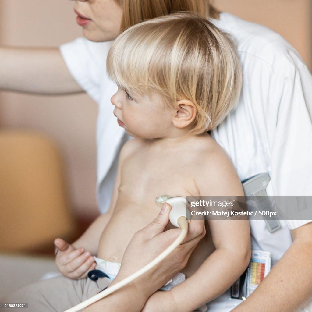 Small child being checked for heart murmur by heart ultrasound exam by cardiologist as part of