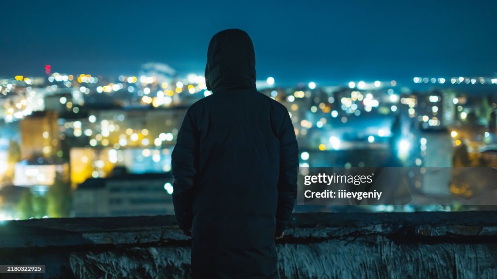 Man silhouette against night city background.