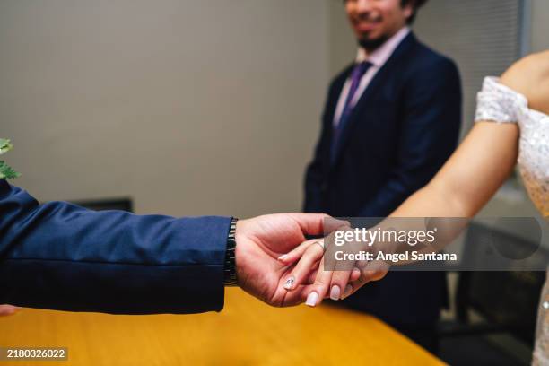 bride and groom holding hands during wedding ceremony with officiant - ceremonia matrimonial fotografías e imágenes de stock