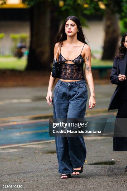 Guest wears lace bralette, sheer top, black straps, high-waisted jeans, wide-leg jeans, black sandals, black shoulder bag, minimalist jewelry,...