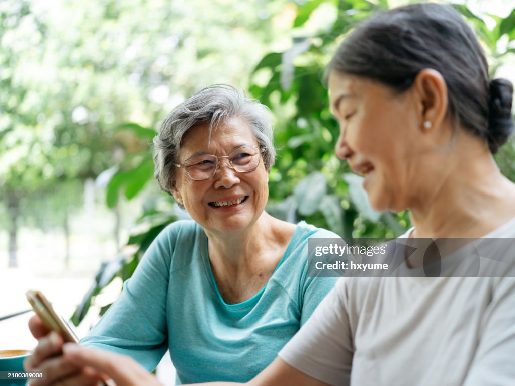 Two Asian senior women surfing the net while sitting at the cafe