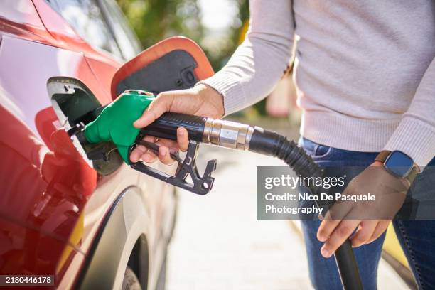 side view of man refilling car at the gas station - tank stockfoto's en -beelden