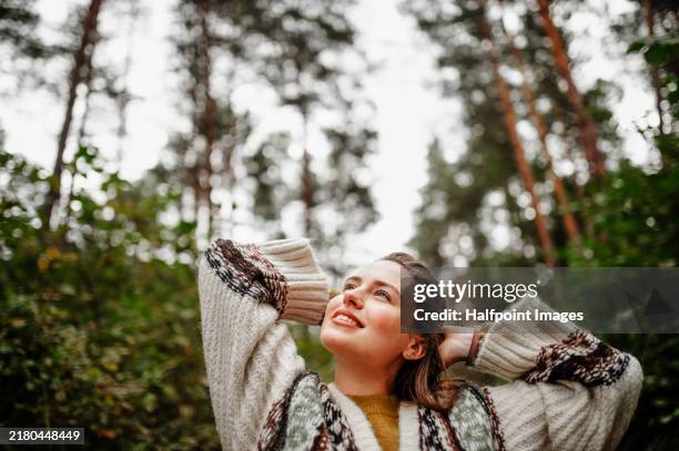 beautiful woman outdoors in nature, enjoying serene moment and finding peace, looking at forest around her. healing power of forest. - ambientalista foto e immagini stock