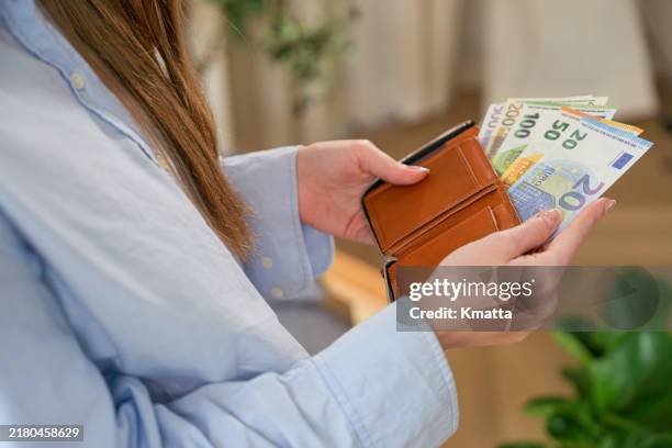 woman's hands pulling euro banknotes out of a wallet. - thrift stock pictures, royalty-free photos & images