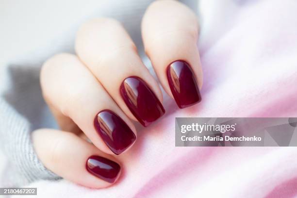 hand with burgundy gel fingernails - unha imagens e fotografias de stock