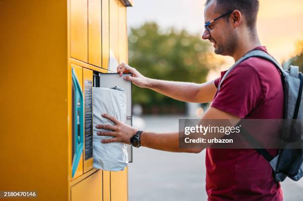 mid-adult man picking up his package from an electronic parcel locker - locker stock pictures, royalty-free photos & images
