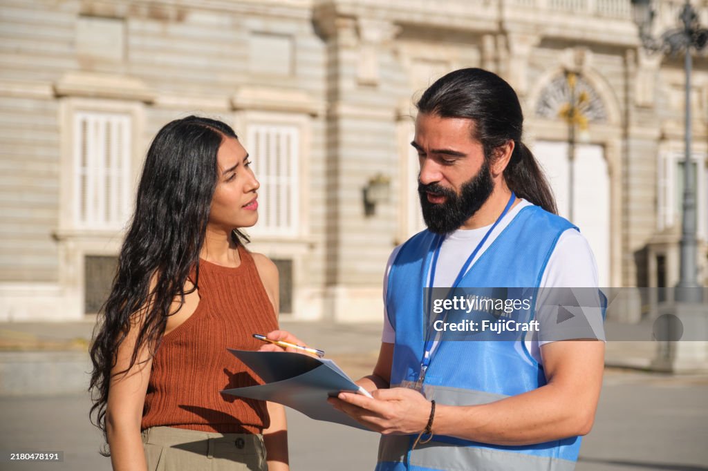 Male volunteer asking for signature on clipboard in urban setting