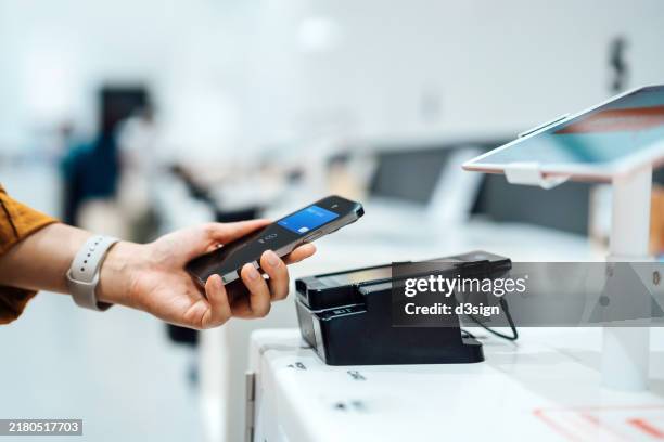 close-up shot of a female hand holding smartphone near to a credit card machine, making contactless payment to pay for her shopping at self-checkout machine in a store. smart pos. digital wallet and mobile payment. innovation and financial technology - bancone attrezzatura per vendita al dettaglio foto e immagini stock