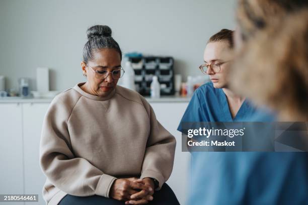 sad female patient sitting with medical worker at hospital - sala de exame médico imagens e fotografias de stock