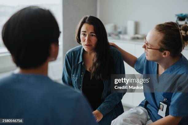 medical worker informing bad news to female patient at hospital - schlechte nachricht stock-fotos und bilder
