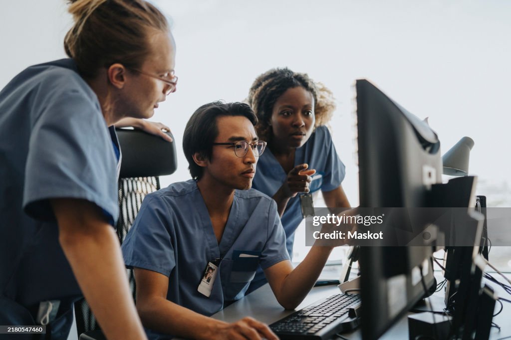 Medical professionals discussing over computer while working in clinic at hospital