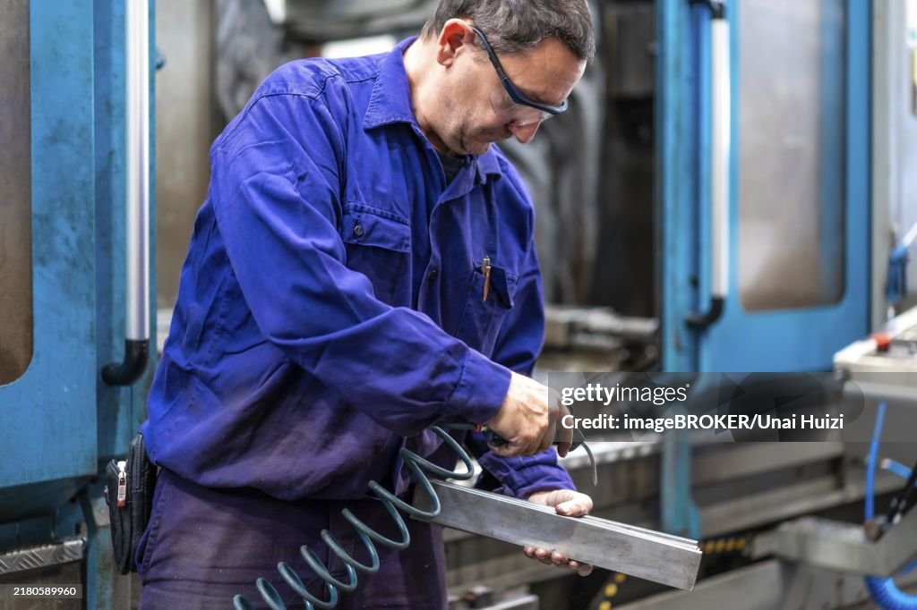 Factory worker operator in the numerical control sector cleaning a part with compressed air, metal industrial factory