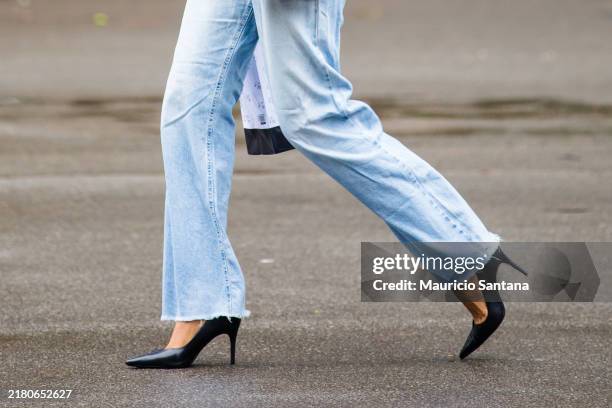 Guest wears light blue denim jeans, frayed hem, pointed-toe black pumps, high stiletto heel, casual loose fit, ankle-length at Sao Paulo Fashion Week...