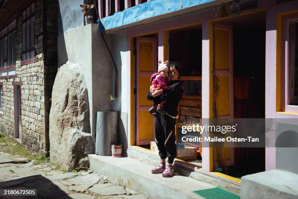 Young woman with a child stands outside a convenience store close to Phakding village on October 07, 2024 in Namche Bazaar, Nepal. Trekking in Nepal...