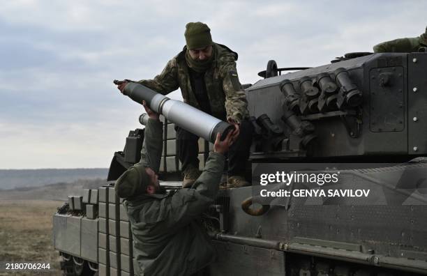 Tankers from the 33rd separate mechanized brigade of the Ukrainian Ground Forces load projectiles onto a Leopard 2A4 tank during a field training at...