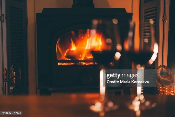 two glasses of red wine in front of a fireplace - offenes feuer stock-fotos und bilder