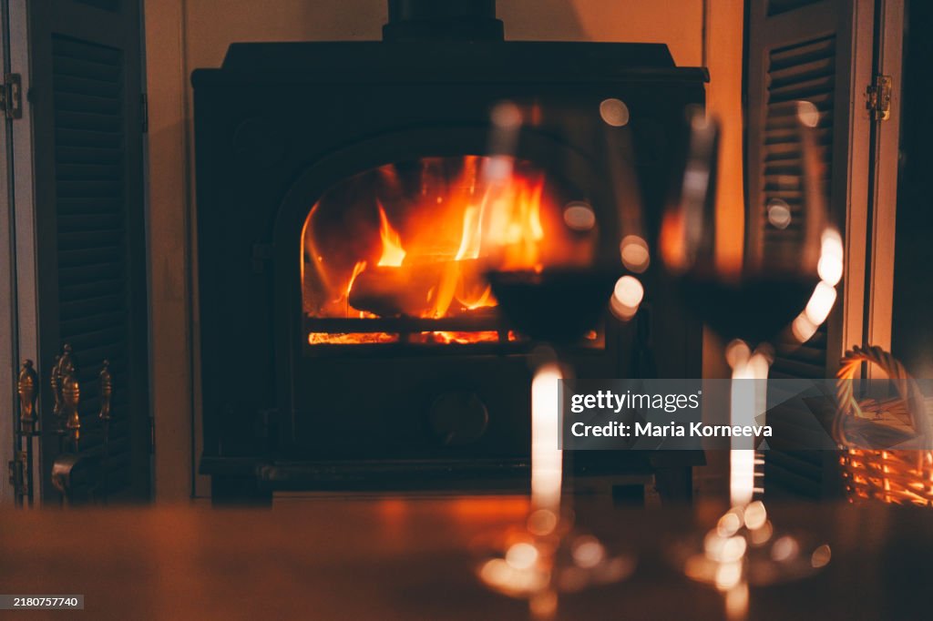 Two glasses of red wine in front of a fireplace